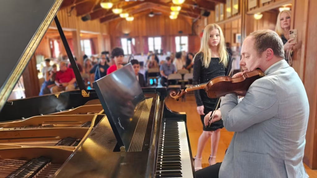 Violin teacher performing at K&M Music Company's student recital, showcasing the collaborative experience between teacher and student in a live performance setting