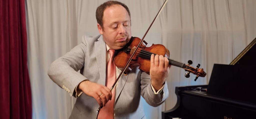 Michael Dvoskin performed at K&M Music Company's student recital, with a grand piano in the background, capturing the passion and artistry of the live performance.